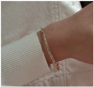 Detail of three-tone sterling silver twisted bracelet on a soft knit sleeve