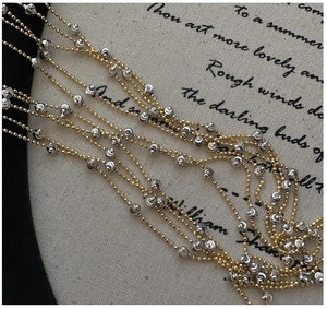 Macro shot of silver textured beads and gold ball chain on vintage fabric background