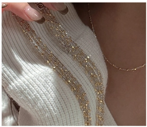 Detail of two-tone gold and silver beaded layered necklace on white knit background
