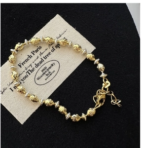 Detailed macro view of S925 silver and gold-tone beaded bracelet with spiral texture