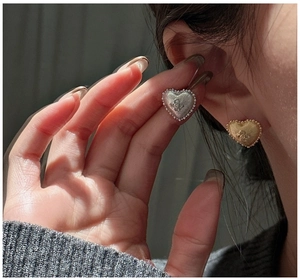 Detail of S925 silver heart stud earrings with brushed metal texture and floral inlay