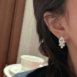 S925 sterling silver leaf pearl earrings on woman's ear in warm indoor lighting