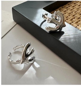 Detail of bird-shaped silver rings with polished mirror finish on a minimalist background