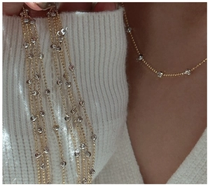 Detailed shot of two-tone gold and silver beaded necklace on skin with white knit sweater