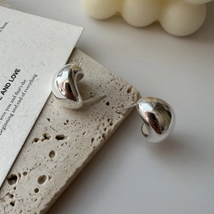 Polished S925 sterling silver curved stud earrings on a minimalist stone tray display