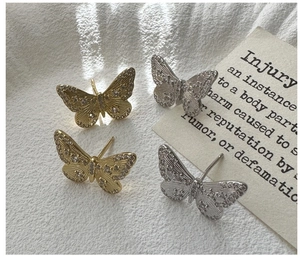 Detail of silver and gold butterfly stud earrings with zircon inlay on textured fabric