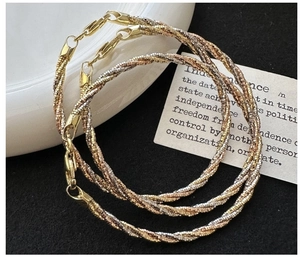 Detail of tricolor gold twisted rope bracelet featuring interlocking metal strands