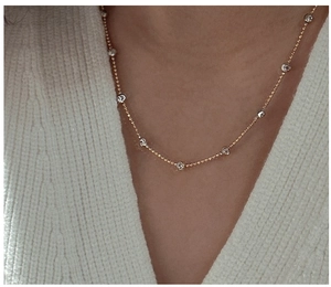 Detail of minimalist two-tone silver and gold bead necklace worn on model neck