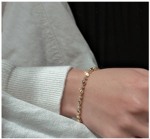 Close-up of faceted gold beads bracelet with fine engraving on woman wrist
