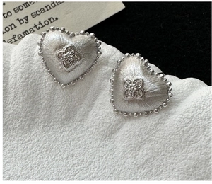 Macro shot of S925 sterling silver heart studs with brushed metal and floral zircon