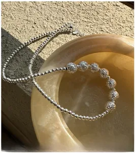 Macro shot of 925 sterling silver beaded necklace with glitter sand beads in jade bowl
