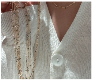Détail d'un collier multicouche en argent S925 avec chaîne dorée et perles sur un modèle