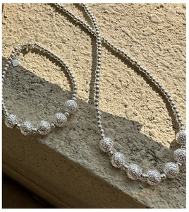 Macro view of 925 sterling silver beaded necklace and bracelet set on stone background