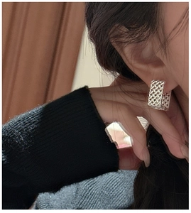 Vue macro détaillée d'une boucle d'oreille en argent S925 avec texture maille tressée