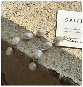 Detail of baroque pearl drop earrings featuring four stacked natural pearls and gold plating