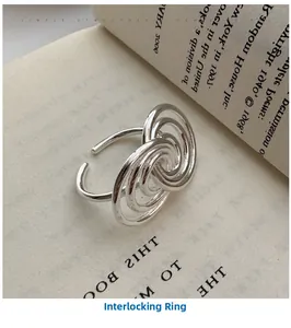 Macro detail of intertwined S925 silver spiral rings displayed on an open book page