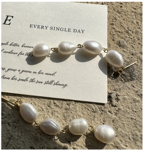 Detailed macro view of S925 silver baroque pearl earrings with golden chain links
