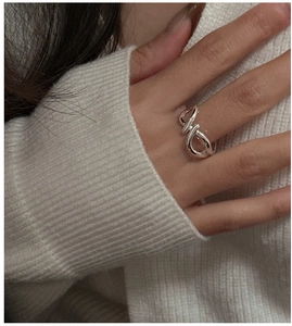 Detailed close-up of a twisted silver S925 ring featuring a minimalist interlaced design