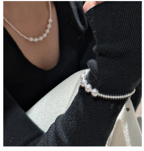 Detail of S925 sterling silver beaded bracelet with heart charm and matte finish texture