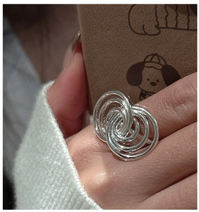 Detailed close-up of multilayered interlaced S925 silver rings on finger