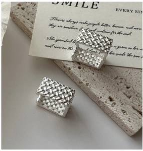 Vue détaillée des boucles d'oreilles créoles S925 en argent à texture tissée sur pierre