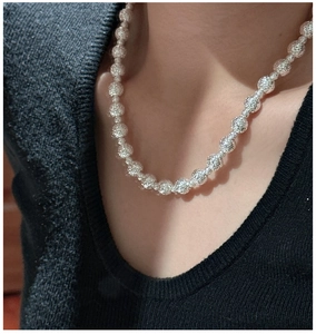 Dettaglio della collana di perline in argento 925 con texture diamantata su maglia nera