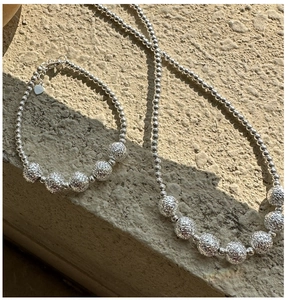 Macro detail of S925 sterling silver beaded bracelet with textured metal charms and heart tag