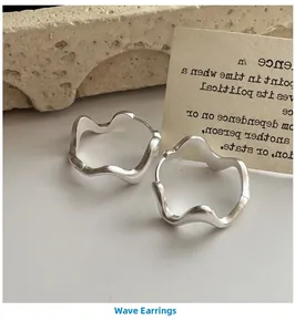 Detailed view of matte silver wave hoop earrings with irregular geometric liquid texture