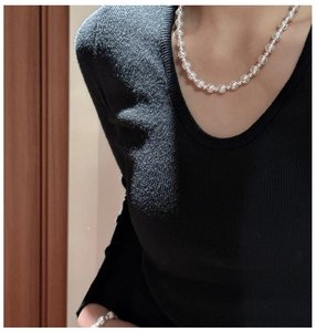 Dettaglio del set collana e bracciale con perline in argento 925 su un maglione nero