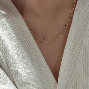 Collier double rang doré minimaliste avec zircons porté par un mannequin