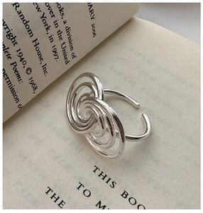Detail shot of a silver layered spiral ring on an open book showing a minimalist design