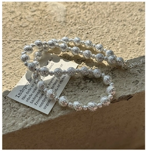 Dettaglio collana in argento 925 con perline martellate su sfondo di pietra naturale