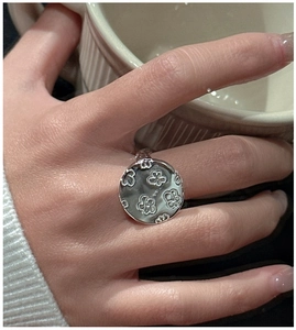Detail of S925 sterling silver ring with 3D embossed flower on a round disc face