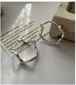 Detail view of wavy S925 sterling silver hoop earrings with matte finish on stone prop