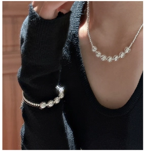 Close-up of S925 sterling silver beaded necklace and bracelet set on a black knit top