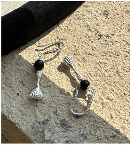 Macro shot of silver retro drop earrings with black beads on a natural stone surface