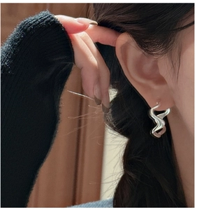 Close-up of S925 sterling silver hoop earring with wave texture on model ear