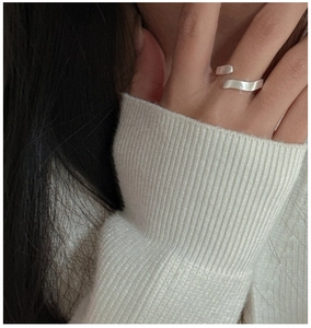 Close-up of a minimalist S925 silver wave ring on a finger with brushed texture