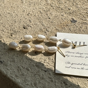Elegant gold earrings featuring four tiered baroque pearls on a textured stone background
