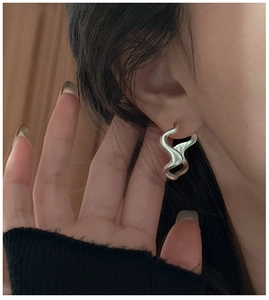 Macro view of S925 sterling silver wavy earring on ear showing the authentic hallmark
