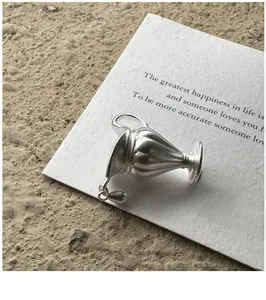 Macro detail of a vintage matte silver vase-shaped pendant on a rustic text card