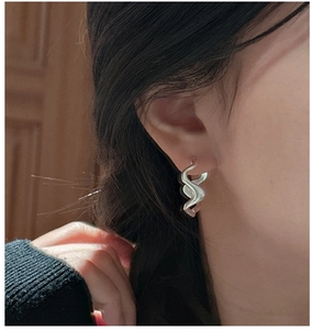 Macro detail of S925 sterling silver ear cuff showing liquid wave texture on the model