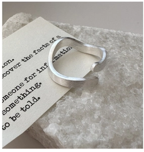 Macro view of minimalist S925 sterling silver ring with brushed texture and wavy edge