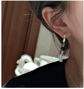 Detail of S925 sterling silver earring with black bead and slim metal tassels on model