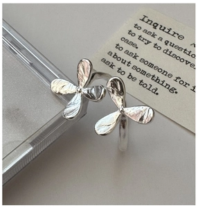 Close-up of S925 sterling silver flower rings with handcrafted texture on grey background