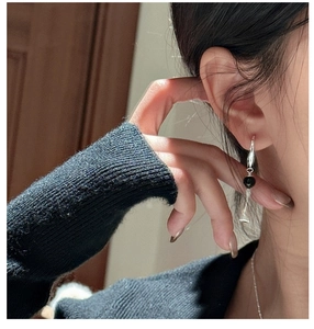 Detail of S925 sterling silver drop earring with black onyx bead and conical metal pendant