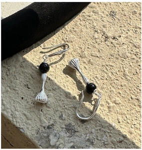 Macro detail of S925 sterling silver drop earrings with black beads on a stone surface