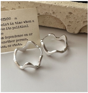 Detailed view of matte S925 sterling silver wave earrings on artistic stone background