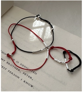 Minimalist red and black braided cord bracelets with silver beads on a vintage book