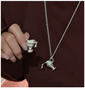 Detail of vintage silver bottle pendant with textured surface worn on red sweater